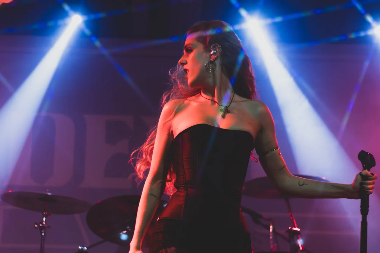 Ana Beatriz num palco de concerto sob luzes azuis e vermelhas